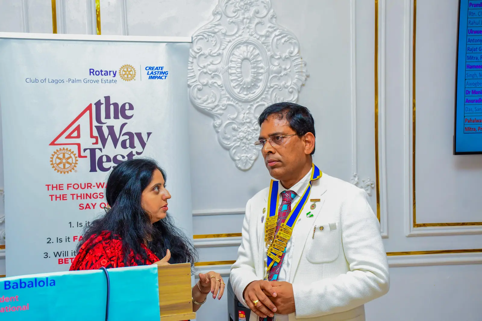A member of the club speaking beside a Rotary banner printed with the Four-Way Test, at the club's fellowship.