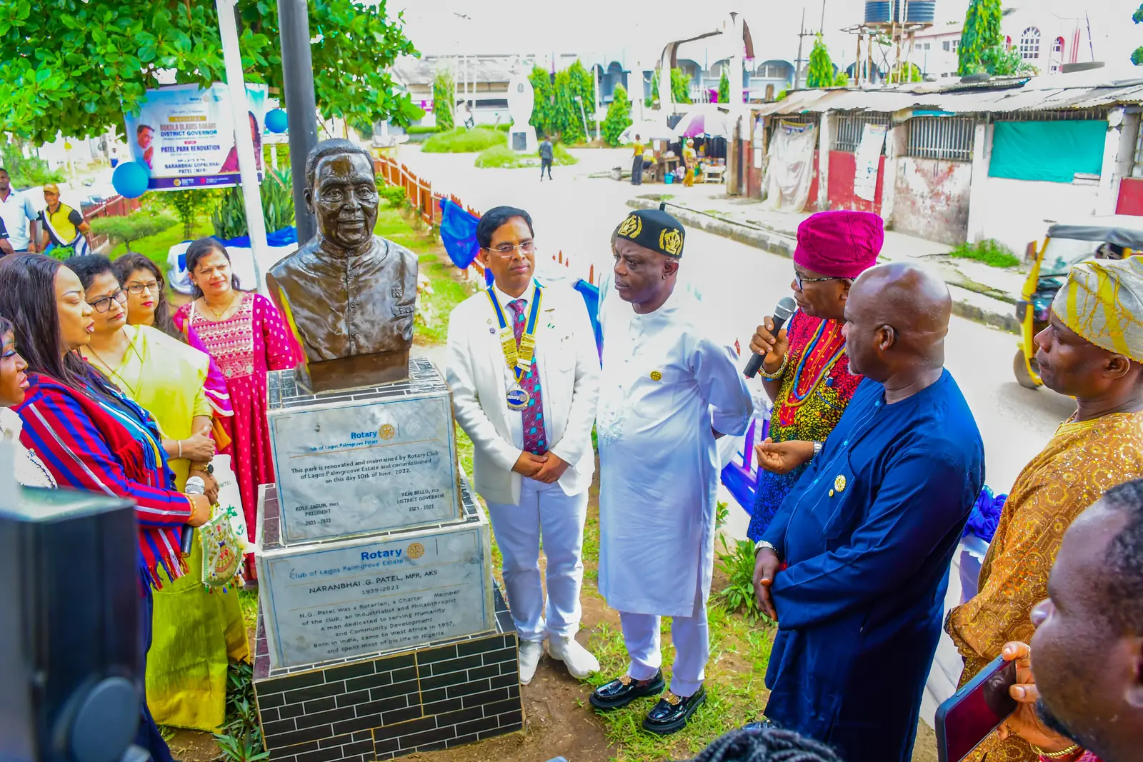 The bronze bust of N. G. Patel on its plinth in Patel Park, with the club president and the District Governor’s party standing beside it.