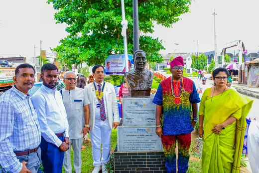 A small group of members standing at the plinth beneath the bust.